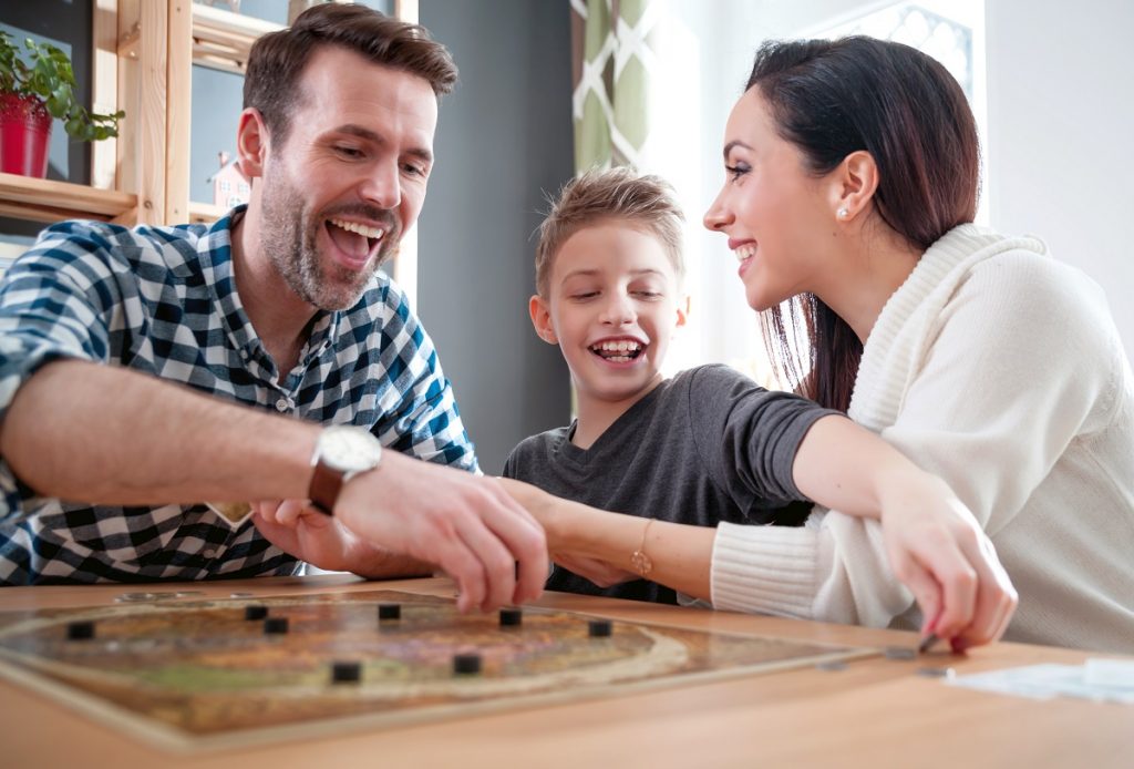O familie fericită, mamă, fiu și tată, în timp ce se joacă împreună una din cele 5 activități creative de 1 iunie, într-un joc antrenant de societate