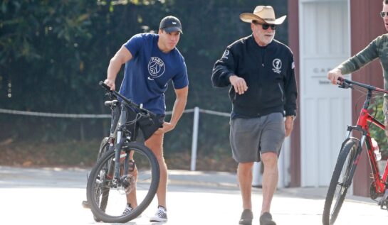 Arnold Schwarzenegger și Joseph Baena sunt îmbrăcați sport și se plimbă cu bicicletele
