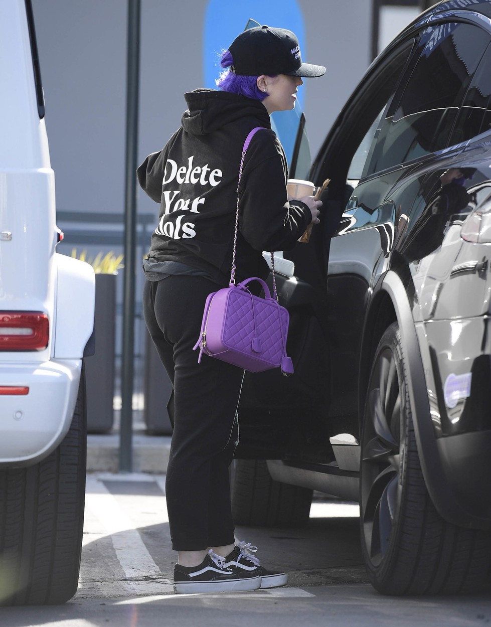Kelly Osbourne, în timp ce caută ceva în mașină, îmbrăcată în haine sport, cu șapcă pe cap