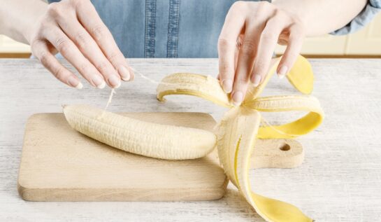O femeie decojește o banannă pe un tocător