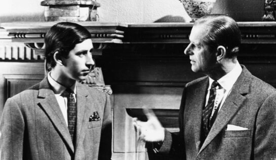 Prințul Charles alături de Ducele de Edinburgh într-o poză alb negru d când Charles era foarte tânăr. Cei doi sunt îmbrăcați la patru ace