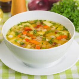 Supă din legume multicolore în bol de servire alb