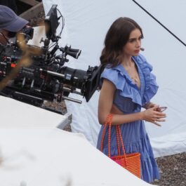 Un cadru din "Emily în Paris", sezonul 2. Lily Collins poartă o rochie albastră și în spate are un cameraman care filmează.