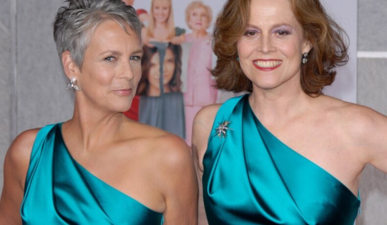 Jamie Lee Curtis și Sigourney Weaver, poartă aceeași rochie de culoare verde, cu umărul gol. Sunt coafate și machiate discret ambele