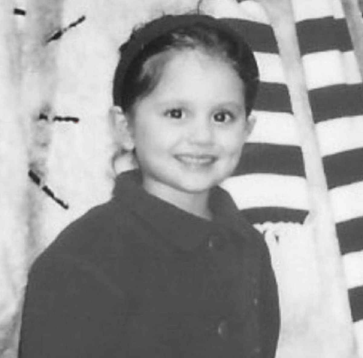Portret alb negru al Arianei Grande în copilărie în timp ce poartă o bluză neagră