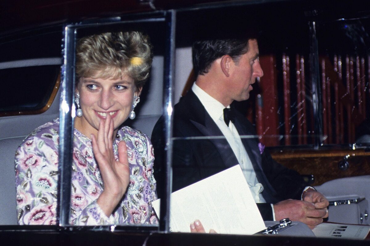 Prințesa Diana alături de Prințul Charles într-o mașină în timp ce face cu mâna publicului la Gala de la Earls Court din 26 octombrie 1992