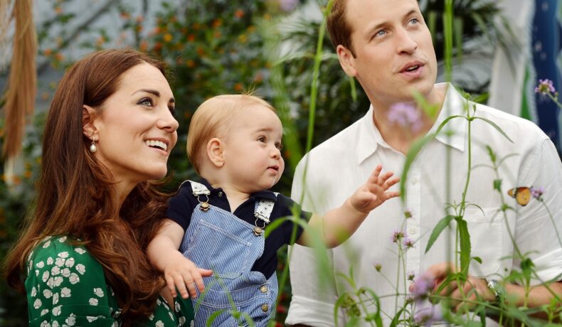 Ducesa de Cambridge, care își ține în brațe copilul, Prințul George, alături de soțul ei, Prințul William în timp ce privesc fluturii la expoziția Sensational Butterflies de la muzeul național de istorie naturală din Londra în 2014, când Kate Middleton și-a fotografiat și copiii