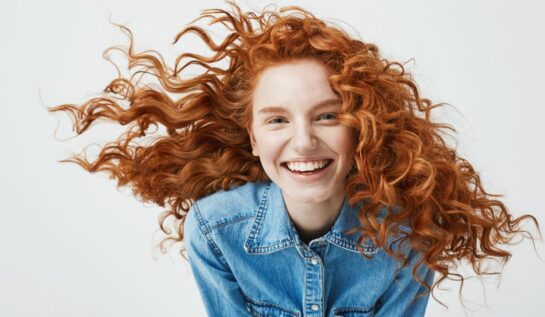 Portretul unei tinere roșcate, zâmbitoare și cu buclele în vânt