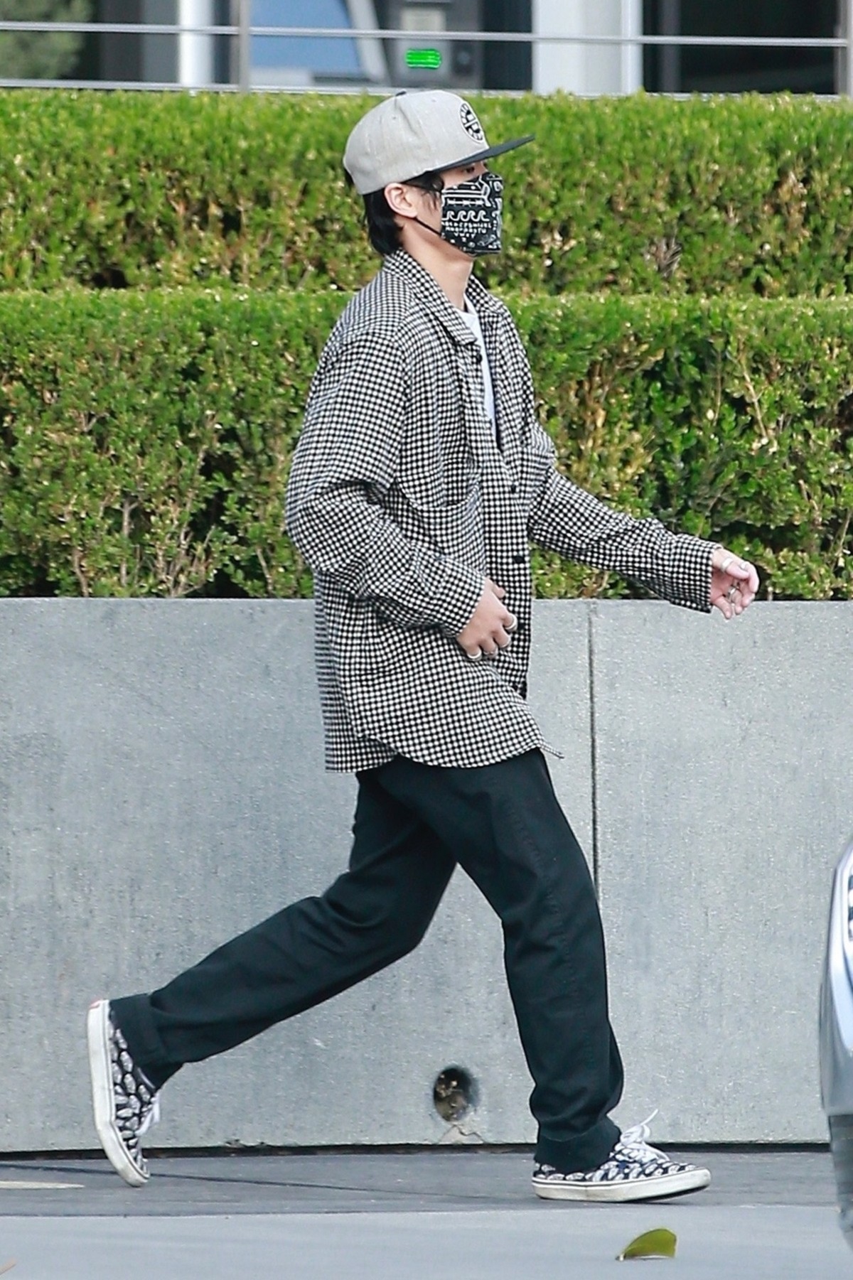 Pax Jolie Pitt îmbrăcat în blugi negri și o cămașă gri în carouri în timp ce poartă o șapcă și mască de protecție pe străzile din Los Angeles