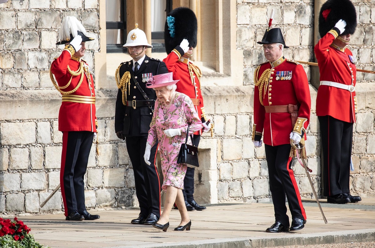 Regina Elisabeta în rochie roz cu imprimeu floral în timp ce emrge însoțită de garda Regală la întâlnirea cu Președintele Joe Biden de la Castelul Windsor