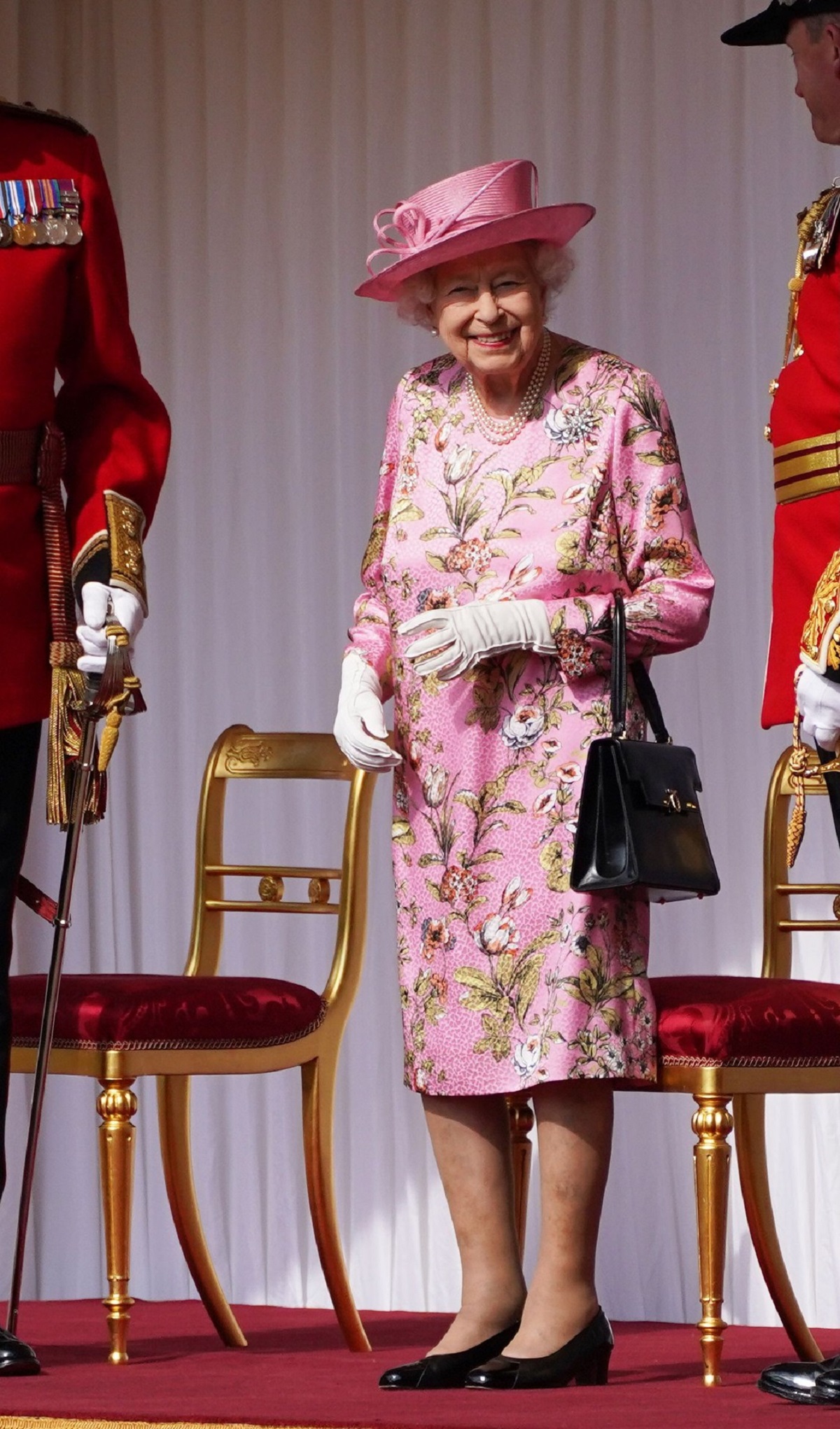 Regina Elisabeta i-a adus un tribut strănepoatei sale și a îmbrăcat o rochie roz cu imprimeu floral și o pălărie de aceeași culoare în timp ce ține în mână o poșetă neagră și zâmbește la cameră înainte să se întâlnească cu Președintele Biden