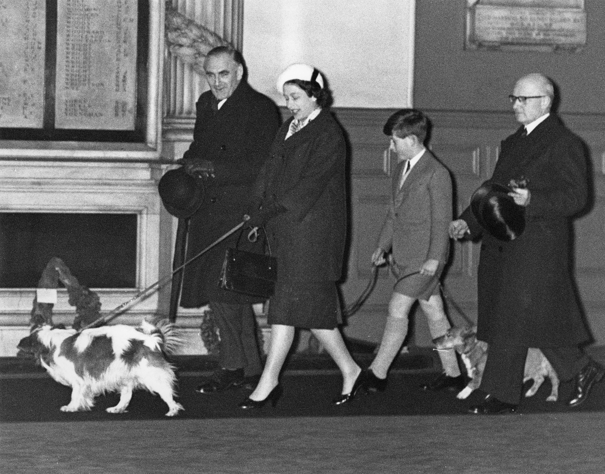 Regina Elisabeta însărcinată cu Prințul Andrew alături de fiul său Prințul Charles și alți doi bărbați în timp ce își plimbau câinii după o vizită de Crăciun