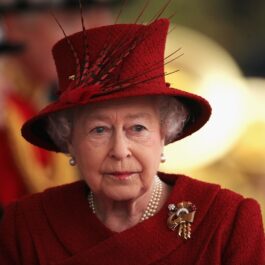 Portret al Reginei Elisabeta purtând un costum roșu și o pălărie elegantă roșie la reședința din Windsor unde s-a întâlnit cu Emirul Qatarului în 2010