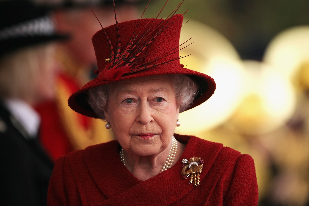 Portret al Reginei Elisabeta purtând un costum roșu și o pălărie elegantă roșie la reședința din Windsor unde s-a întâlnit cu Emirul Qatarului în 2010