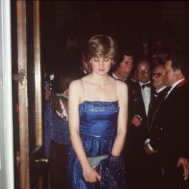 Prințesa Diana purtând o rochie albastră cu paiete în timp ce pășește afară dintr-o încăpere de la un eveniment oficial
