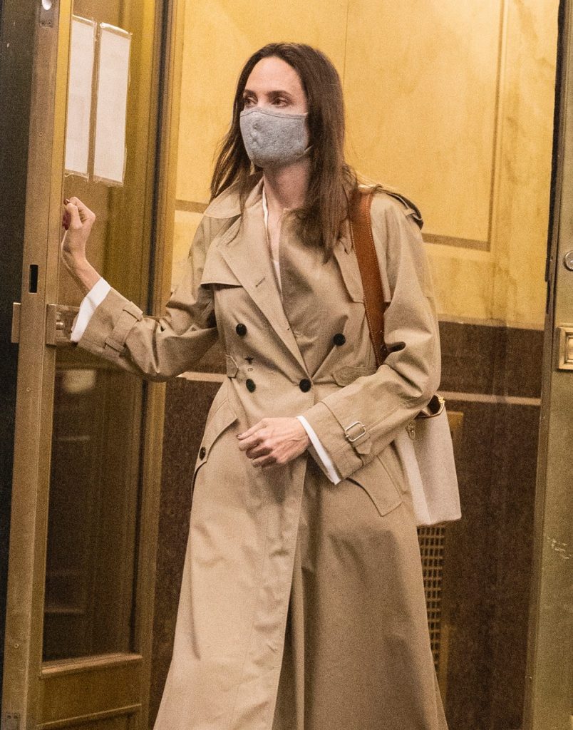 Angelina Jolie, în timp ce iese dintr-un bloc, cu mâna pe ușă, fără agenți de securitate, în New York, clădire în care locuiește Johnny Miller