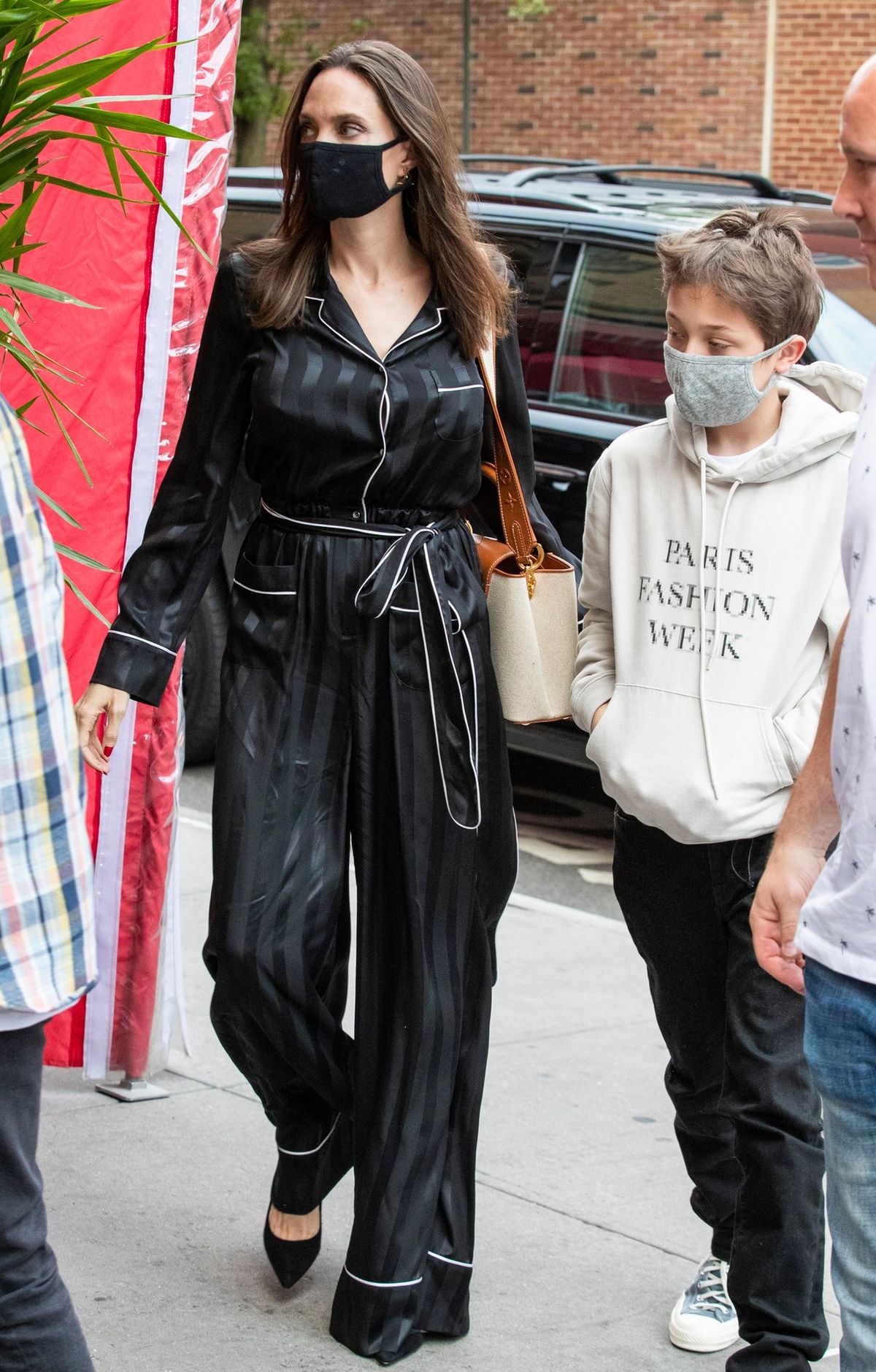 Angelina Jolie poartă o salopetă neagră de satin, împreună cu fiul ei KNox, ce este îmbrăcat într-un hanorac alb