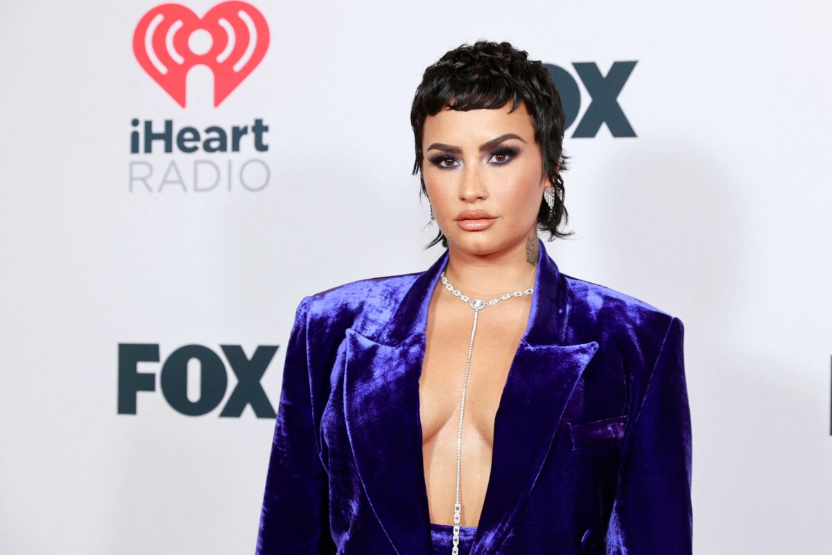 Demi Lovato aparut într-un costum albastru dupa ce a dezvaluit ca e non-binara, cu decolteu, fundal alb, la evenimentul iHeartRadio Music Awards din mai 2021