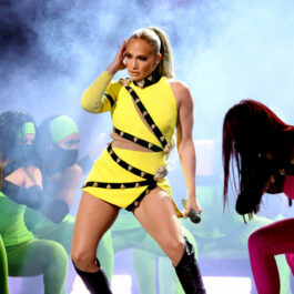 Jennifer Lopez, în concert, pe scena VAX Live, alături de dansatorii ei, într-o ținută galbenă