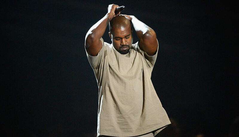Kanye West, pe scenă, la MTV Video Music Awards, în 2015, cu mâinile în cap