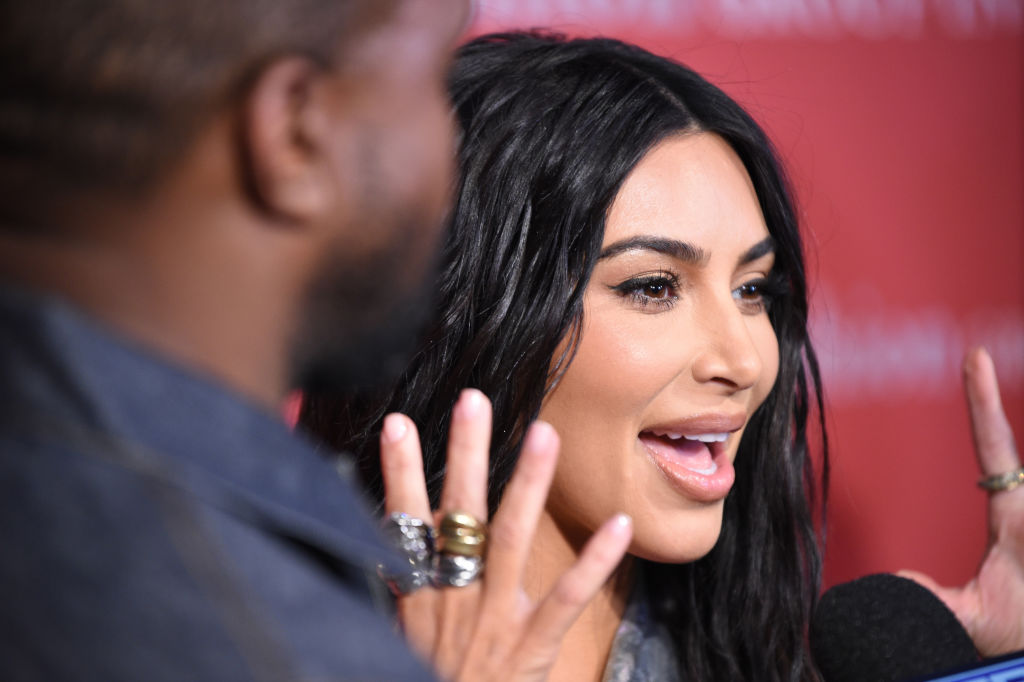 Kim Kardashian, la un eveniment monden în 2019, cu mâinile în sus, exprimând o mirare