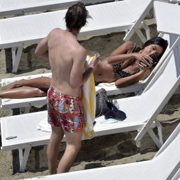 Mădălina Ghenea, fotografiată la plajă, în timp ce se uită pe telefon și discută cu Andrea Castagnola