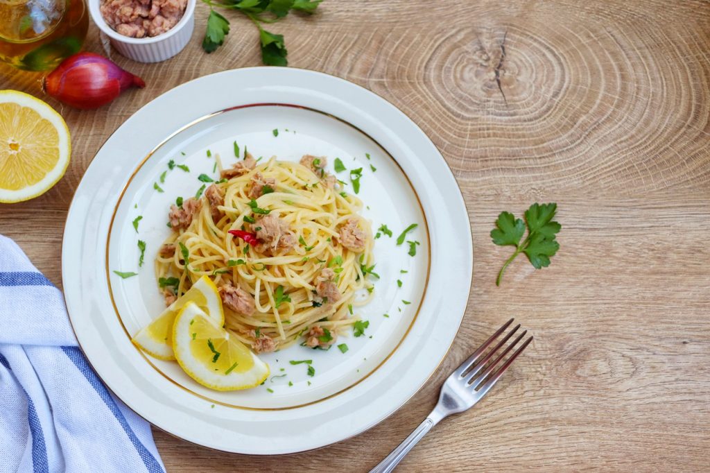 Spaghete cu ton și lămâie într-o farfurie albă