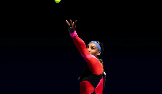 Serena Williams, pe terenul de tenis la Australian Open, în timp ce lovește mingea cu racheta de tenis