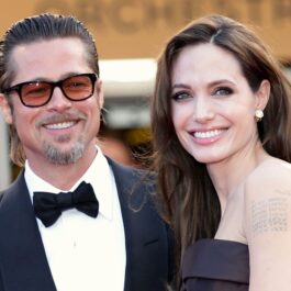 Angelina Jolie într-o rochie neagră în timp ce zâmbește deoarece a obținut o nouă victorie în fața lui Brad Pitt, fiind alături de fostul soț la Festivalul de Film de la Cannes din 2011