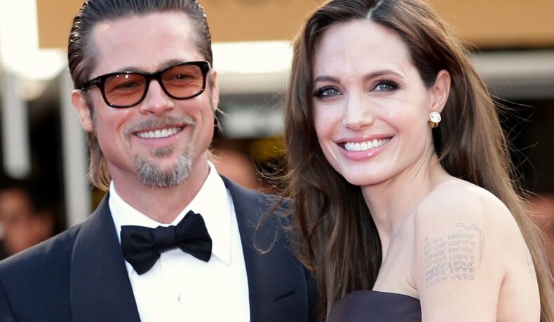 Angelina Jolie într-o rochie neagră în timp ce zâmbește deoarece a obținut o nouă victorie în fața lui Brad Pitt, fiind alături de fostul soț la Festivalul de Film de la Cannes din 2011