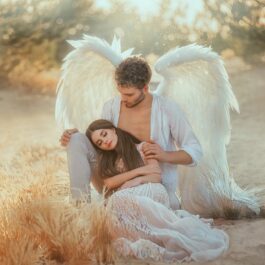 Unul din bărbații care fac femeile cu adevărat fericite, având aripi de înger și stând în genunchi în timp ce o ține după umeri pe iubita sa frumoasă care poartă o rochie albă diafană