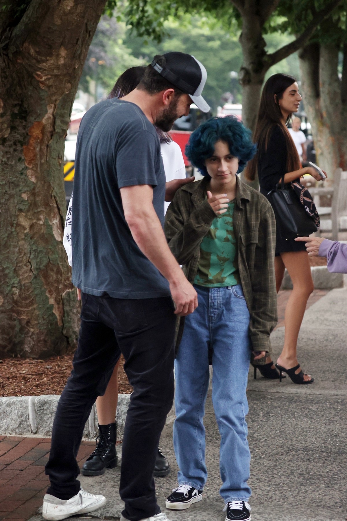 Ben Affleck îmbrăcat casual în blugi și tricou gri alături de fiica lui Jennifer Lopez, Emme care poartă un tricou verde și are părul albastru, după ce au mers împreună la o librărie din New York