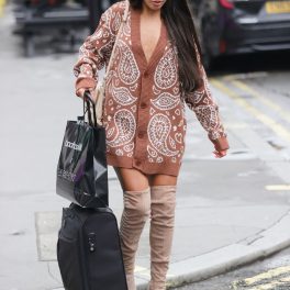 Modelul Emily Miller în timp ce cară un bagaj negru și merge pe străzile londoneze