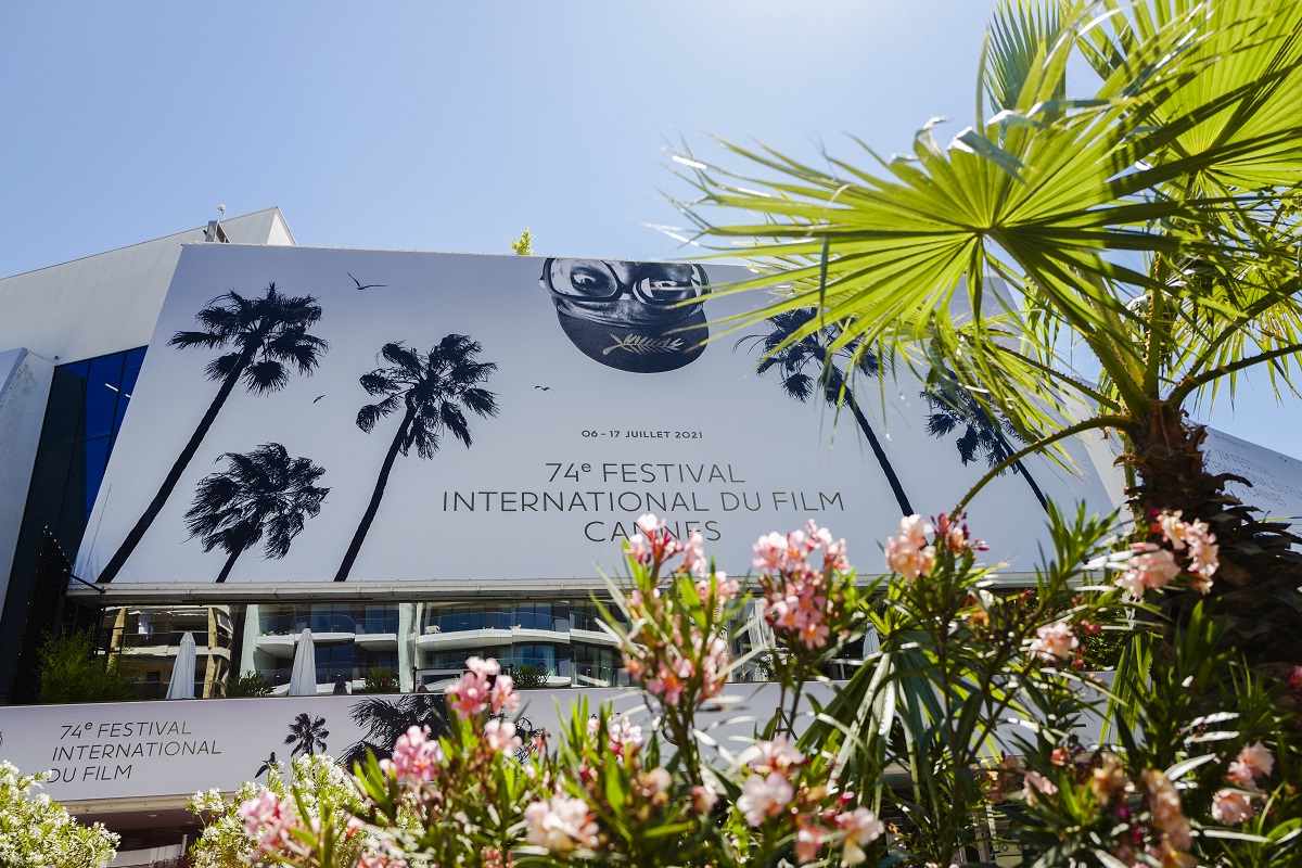 Imagine boemă a afișului de la Festivalul de Film de la Cannes din 2021 acoperit de frunze de palmier și de flori roz