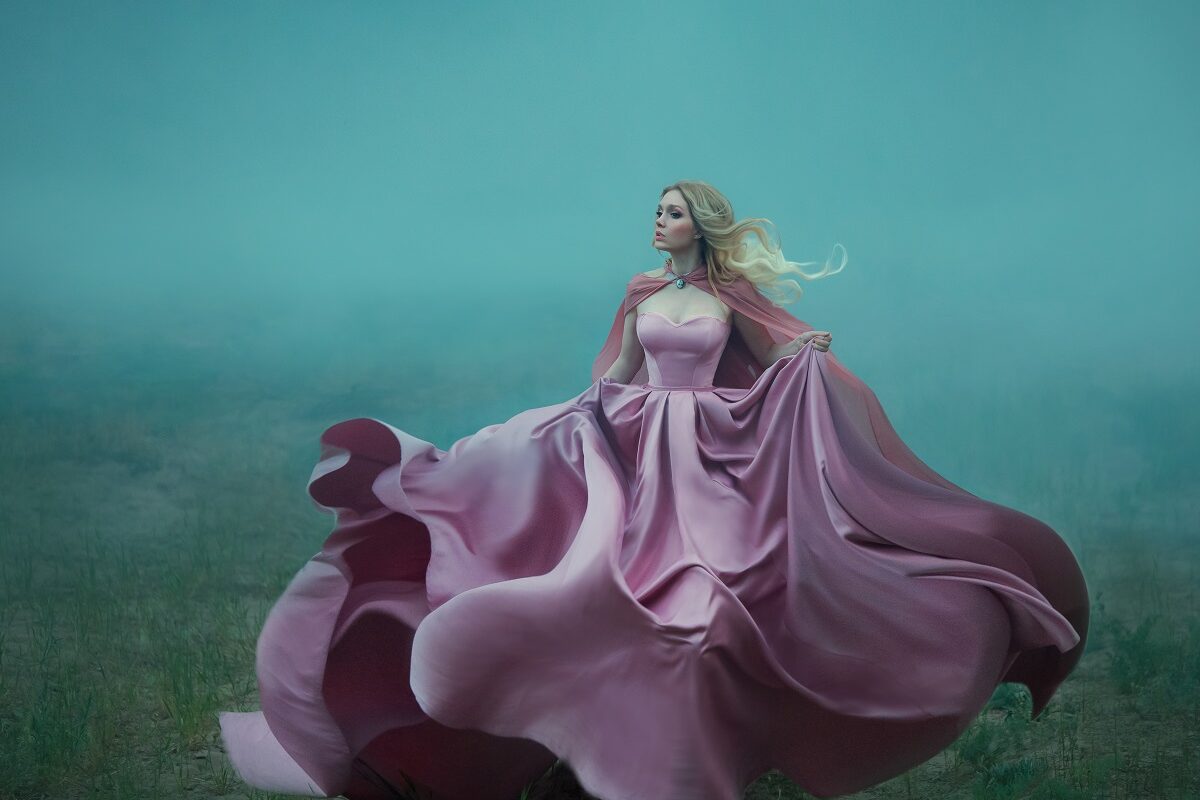 Un ambient înfricoșător în care se află o femeie superbă blondă într-o rochie vaporoasă roz în timp ce fuge și încearcă să ilustreze fricile semnelor zodiacale