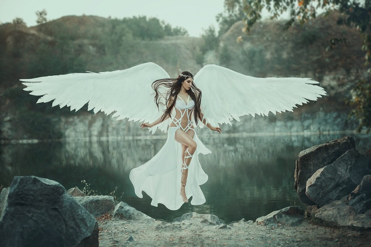 O femeie frumoasă care levitează în fața unui lac și poartă un costum alb și aripi de înger pentru a demonstra cum să pui în practică horoscopul seducției