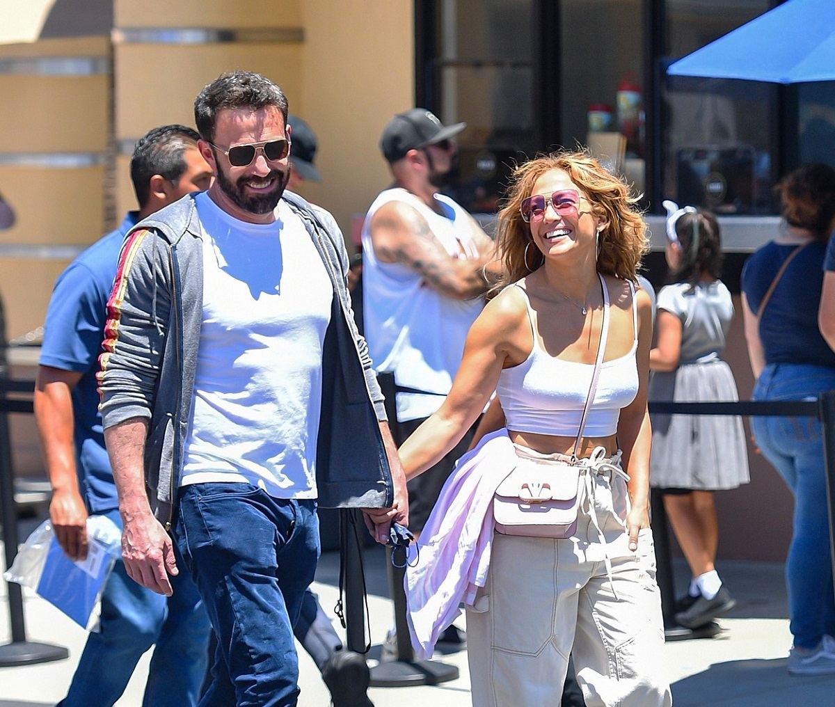 Jennifer Lopez într-o ținută de stradă în timp ce îl ține de mână pe iubitul său Ben Affleck și îi zâmbește larg în parcul de distracții Universa Studios