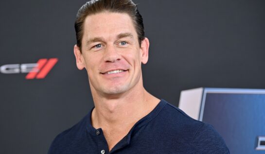 John Cena îmbrăcat într-un tricou albastru în timp ce zâmbește la cameră și își amintește că a dormit într-o mașină înainte să fie faimos