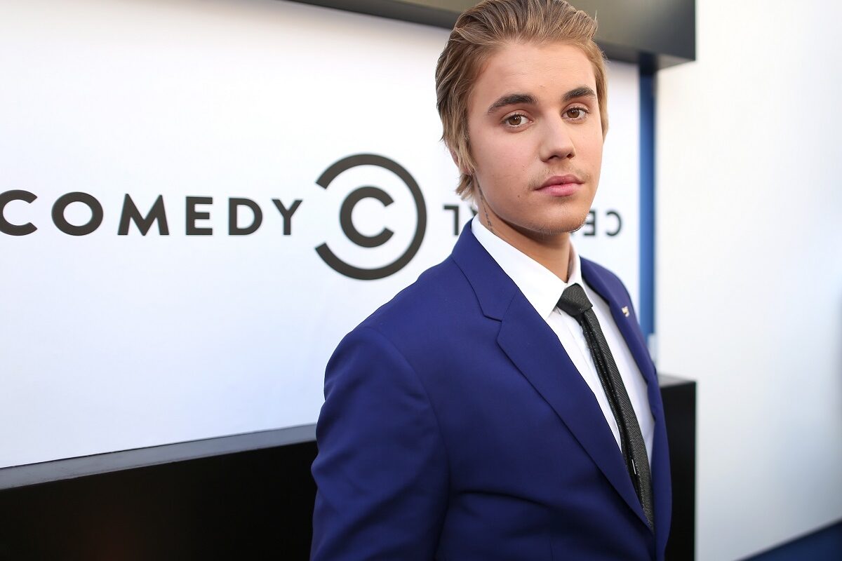 Justin Bieber într-un costum albastru cu cravată în timp ce se află pe covorul roșu la The Comedy Central Roast în anul 2014