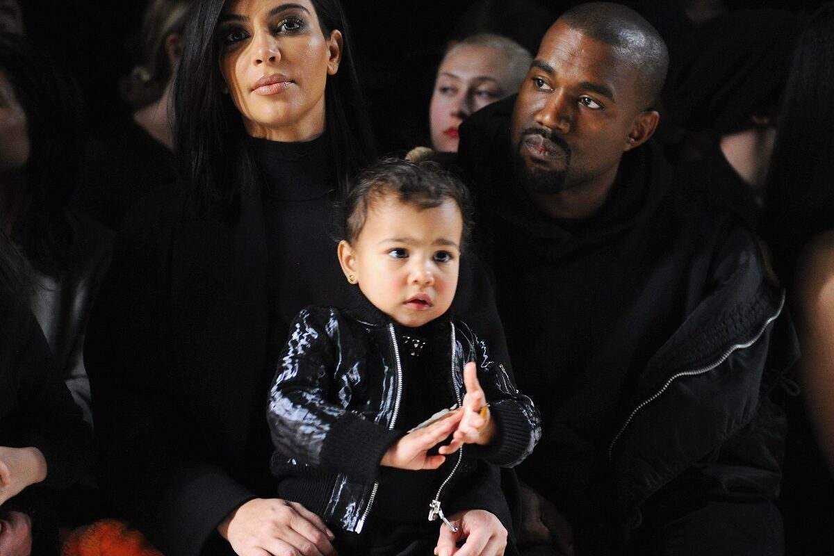 Kim Kardashian alături de fostul ei soț Kanye West în timp ce o țin în brațe pe fiica lor North la o prezentare de modă