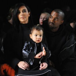 Kim Kardashian alături de fostul ei soț Kanye West în timp ce o țin în brațe pe fiica lor North la o prezentare de modă