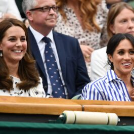 Kate Middleton în timp ce zâmbește în tribuna de la Wimbledon 2018 alături de Ducesa de Sussex, Meghan Markle