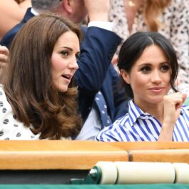 Kate Middleton și Meghan Markle la Turneul Wimbledon în iulie 2018. Cele două au fost surprinsă în timp ce râdeau și glumeau. Kate purta o bluză albă cu buline negre și Meghan purta bluza albă cu dungi albastre