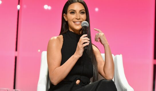 Vedeta Kim Kardashian în timp ce stă pe un scaun și vorbește la microfon la evenimentul The Girls' Lounge din 2016