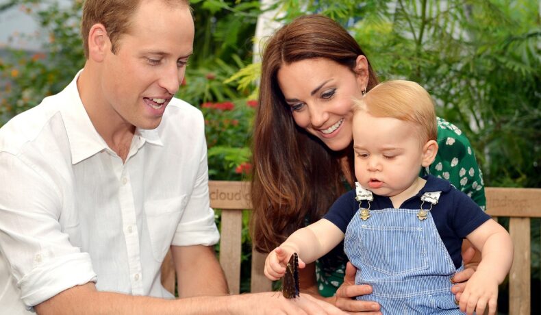 Prințul William alături de Ducesa Kate Middleton și Prințul George în timp ce micuțul privește un fluture de pe mâna tatălui său
