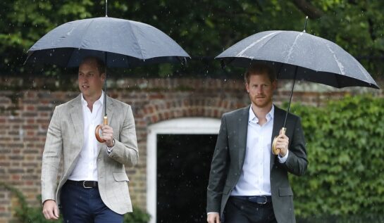 Prințul William purtând costum și ținând o umbrelă în mână este îngrijorat cu privire la careta fratelui său, Prințul Harry care stă lângă el cu umbrela în timp ce se îndreaptă către castelul Kensington