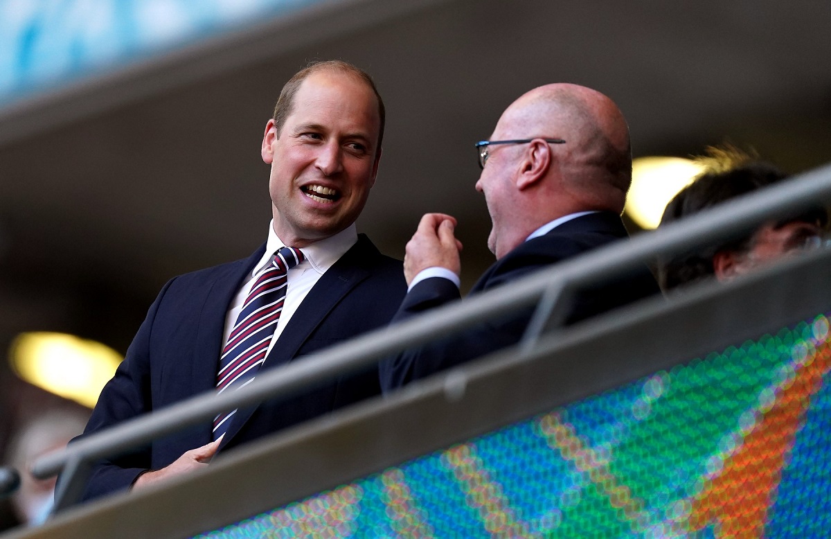 Prințul William purtând costum și cravată în timp ce vorbește cu un bărbat la UEFA Euro 2020
