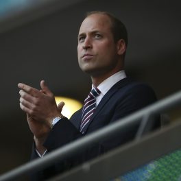 Prințul William la costum în timp ce aplaudă din tribuna unui stadion de fotbal la meciul Anglia-Danemarca din cadrul semifinalei Euro 2020