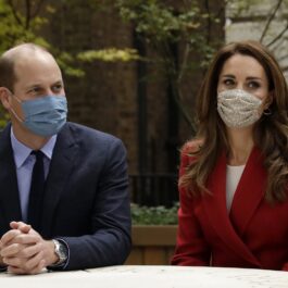 Prințul William îmbrăcat la costum și purtând mască, alături de Kate Middleton la sacou roșu care poartă la rândul său mască, a decis să nu se izoleze la Palatul Kensington alături de soția sa