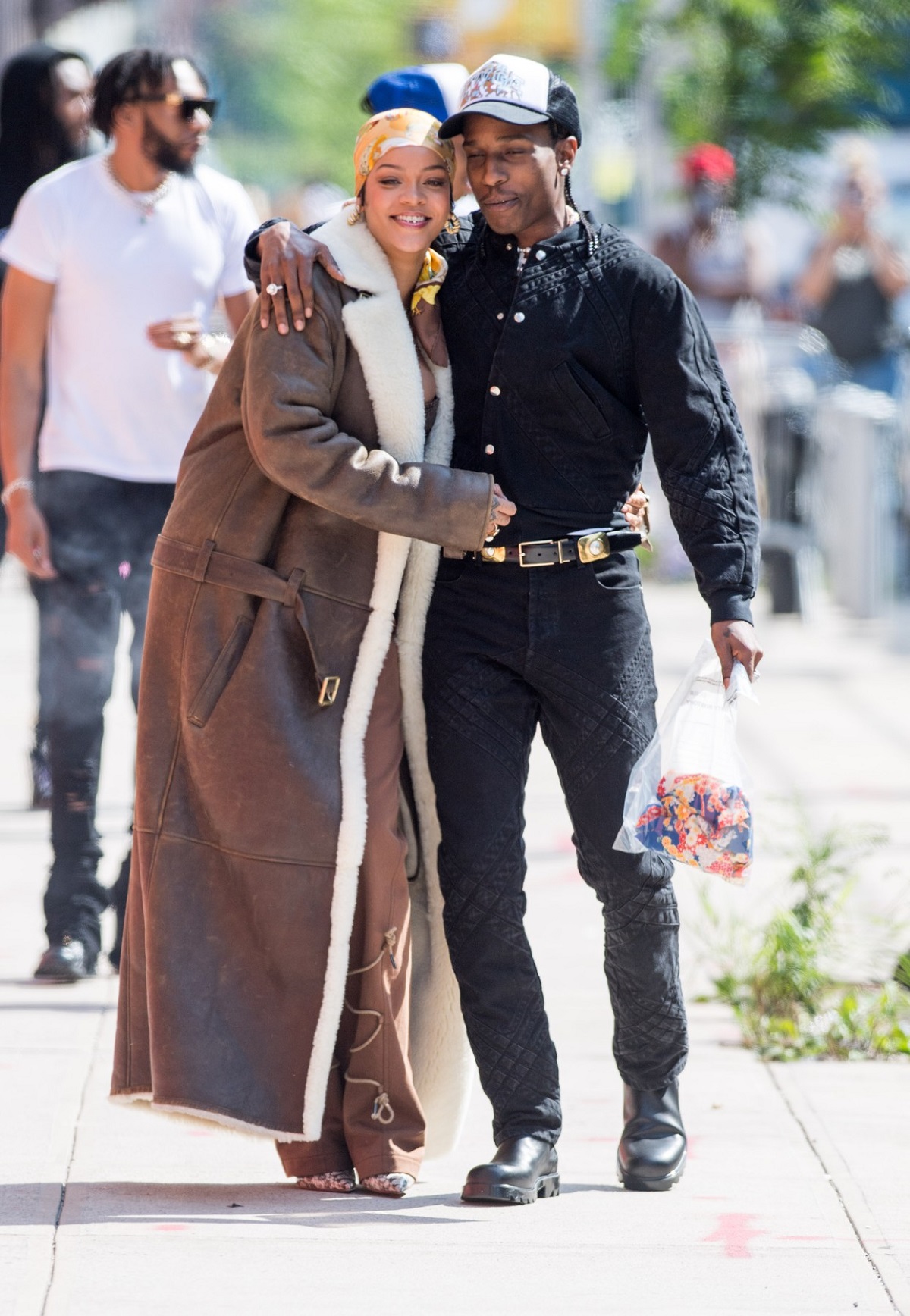 Artista Rihanna într-o ținută crem cu un batic pe cap în timp ce îl ține în brațe pe iubitul său A$AP Rocky la filmările celui mai recent proiect împreună